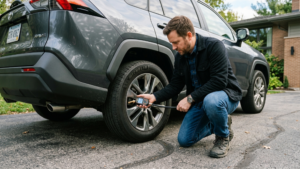 Driver checking tire pressure using digital gauge beside modern vehicle